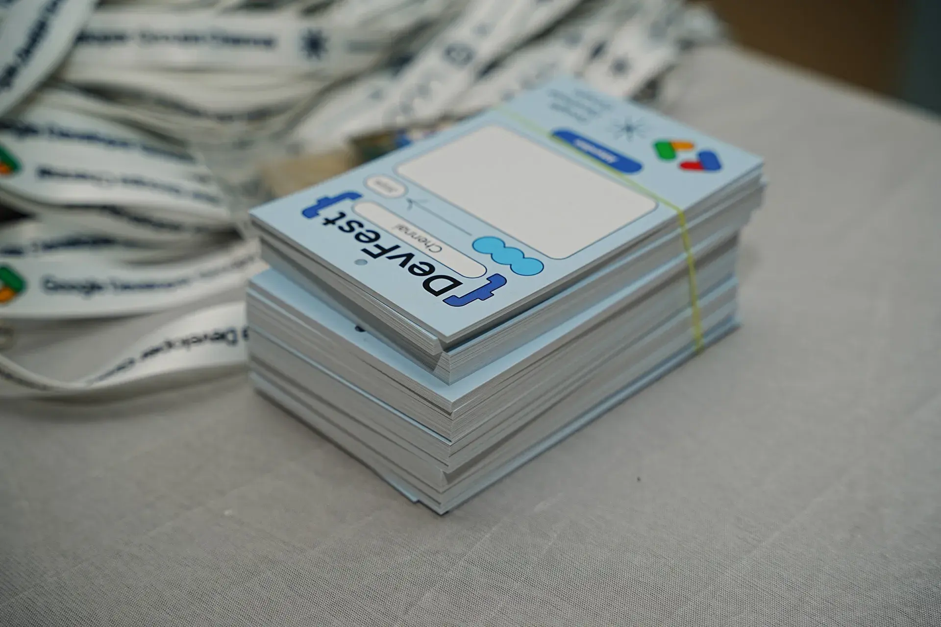 A stack of printed badges beside a pile of lanyards on the registration table.