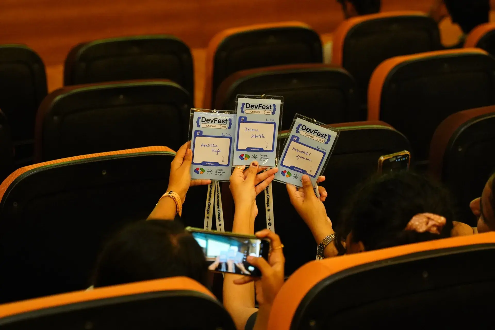 Attendees holding their badges above the seats to be photographed.