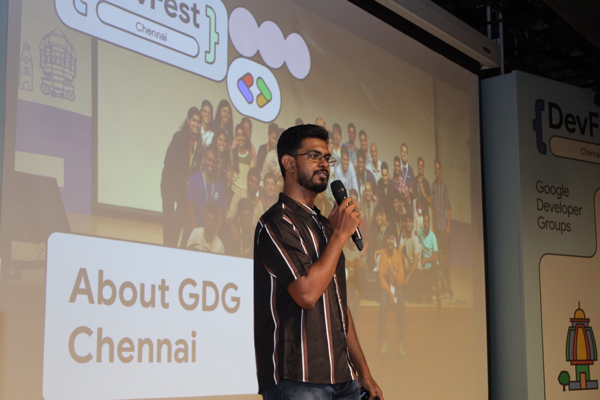 A speaker introducing GDG Chennai beside a slide showing the community group photo.