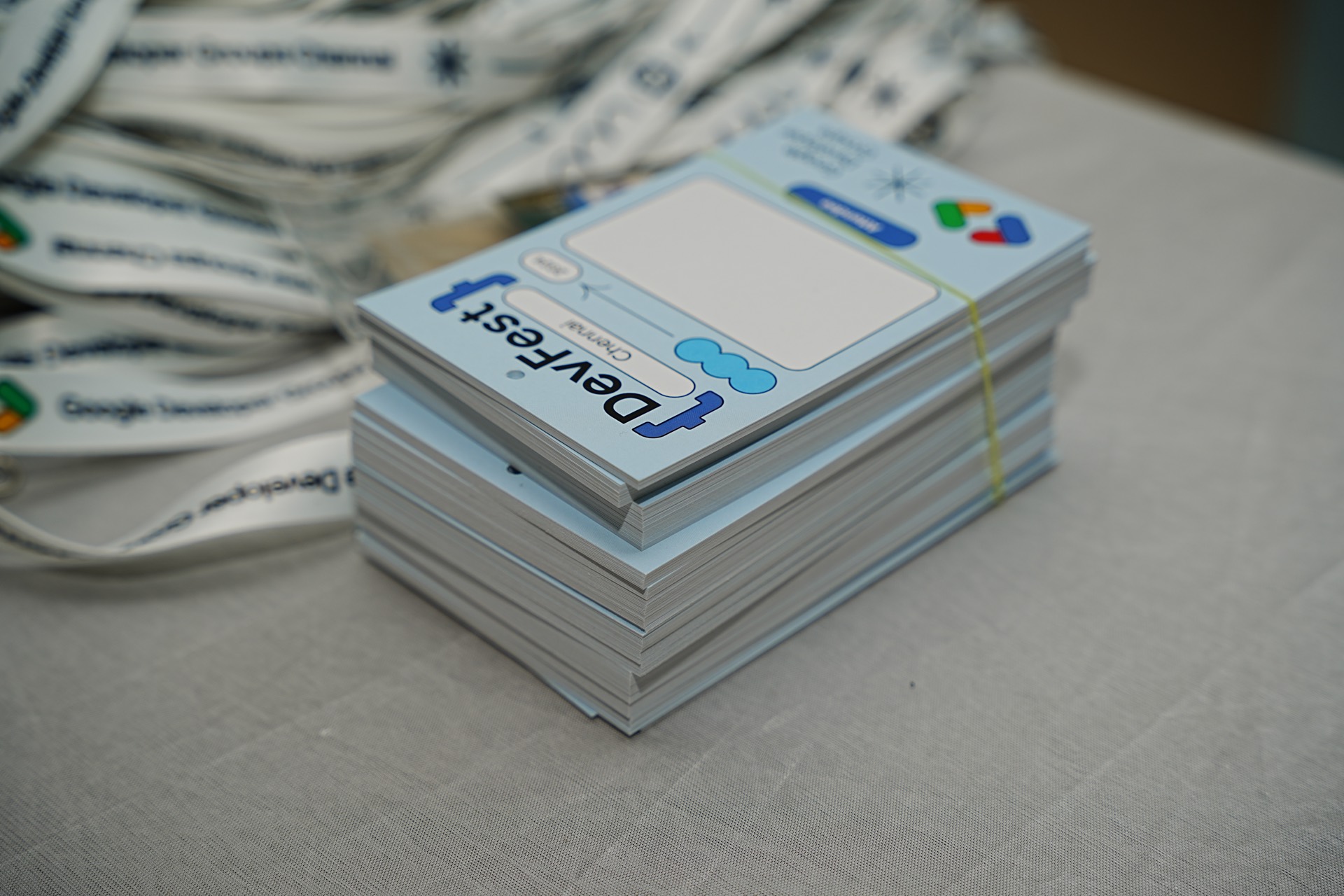 A stack of printed badges beside a pile of lanyards on the registration table.