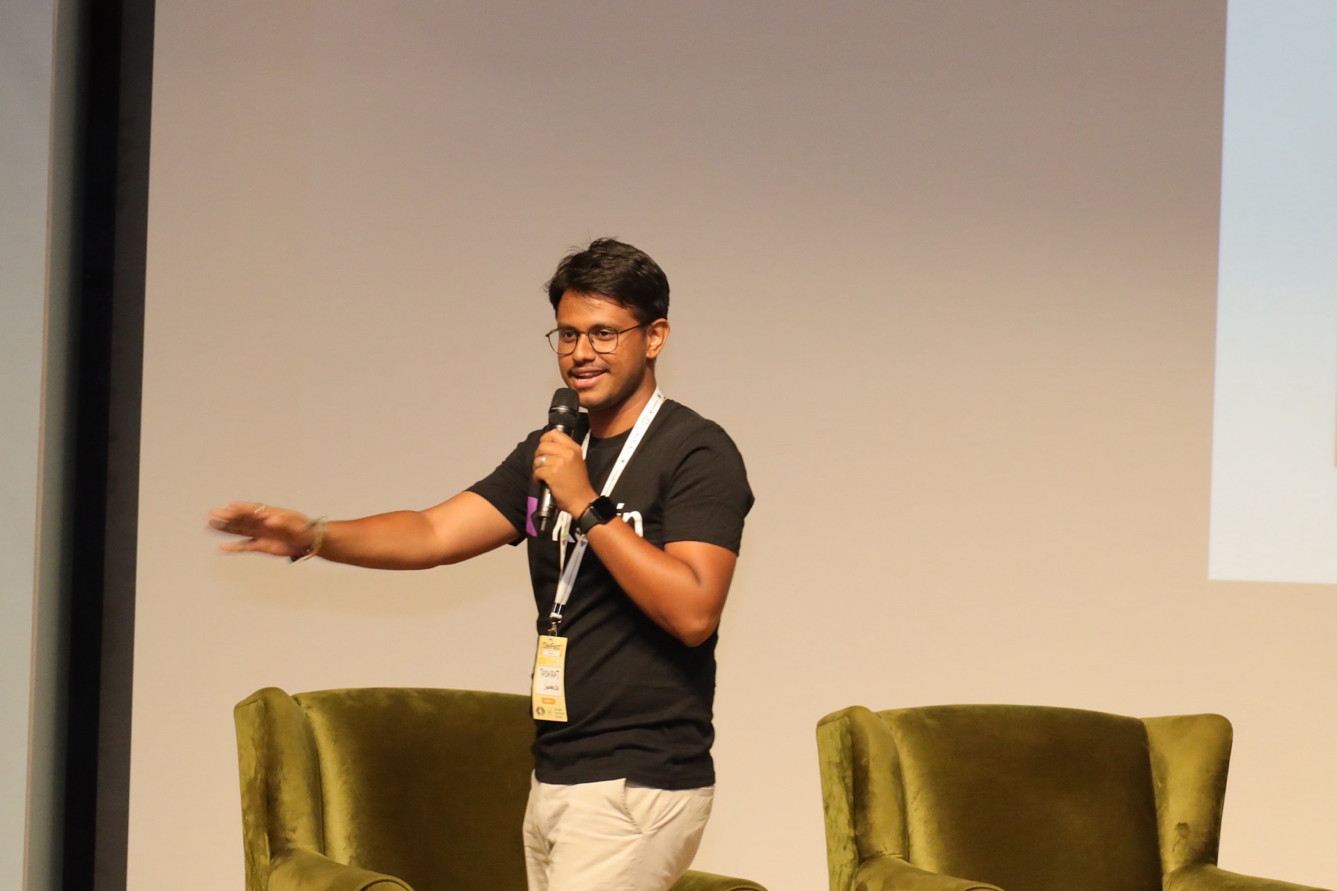 A speaker mid-talk on stage, gesturing to the audience.