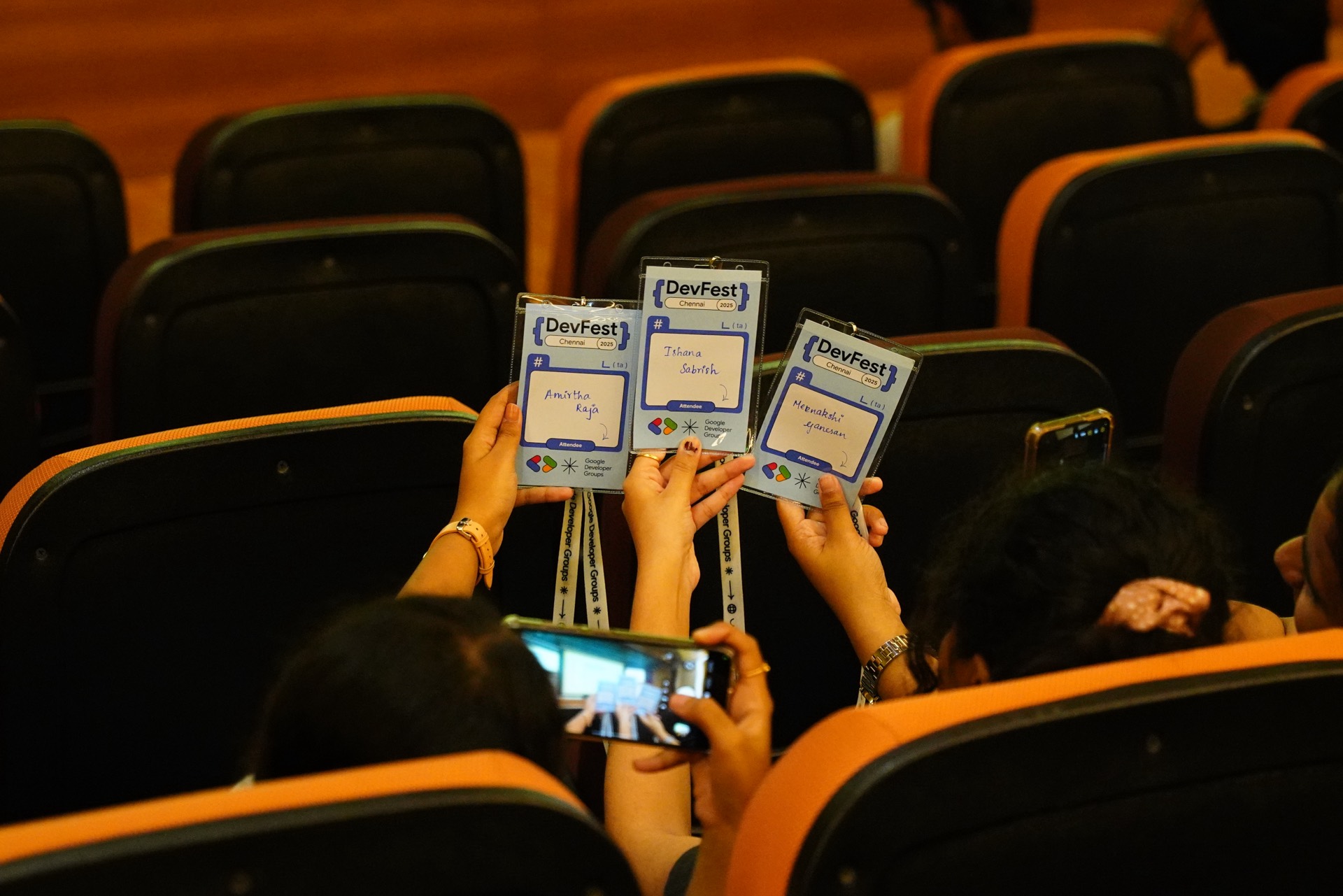 Attendees holding their badges above the seats to be photographed.